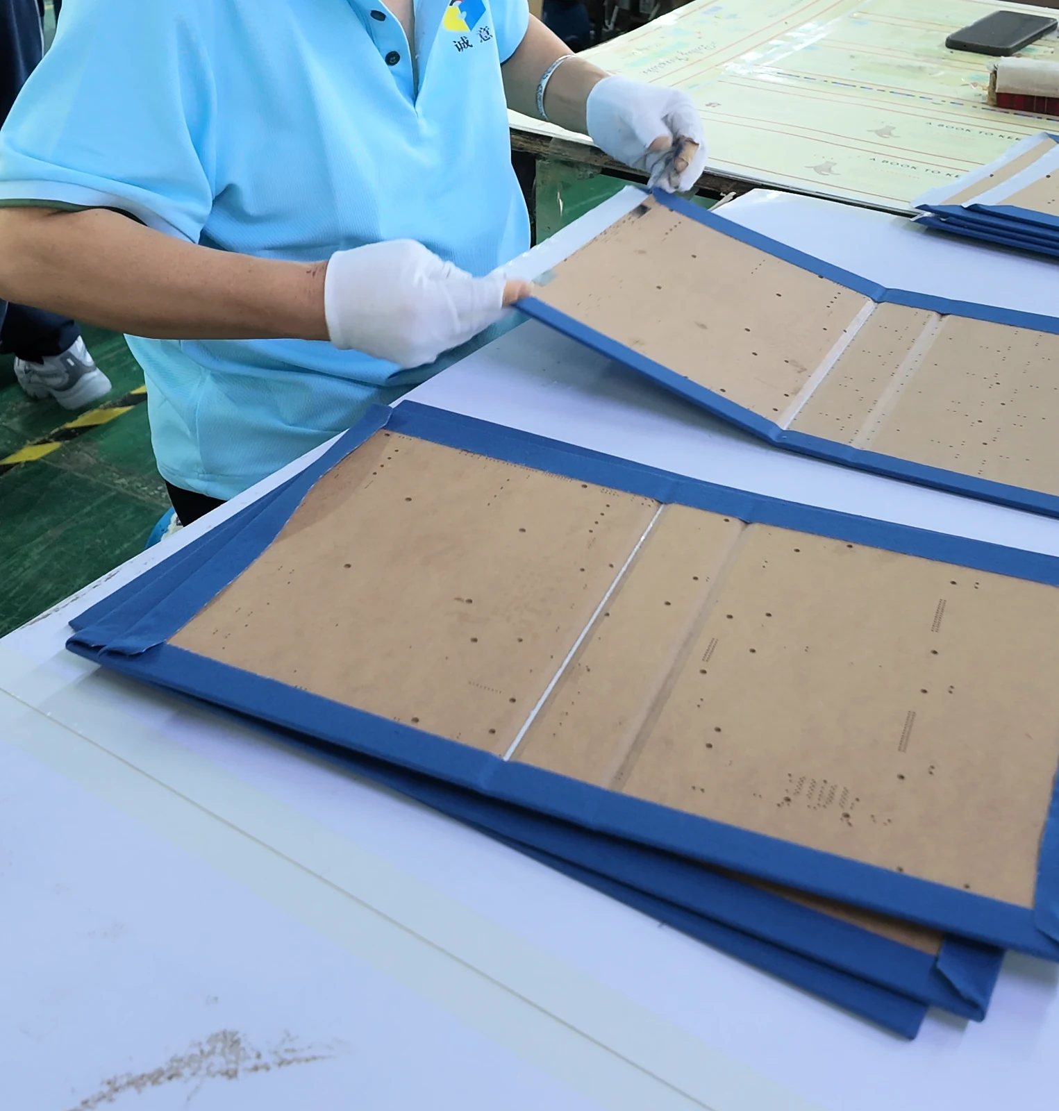 Hands aligning the board panels and spine of a blue hinged cover.