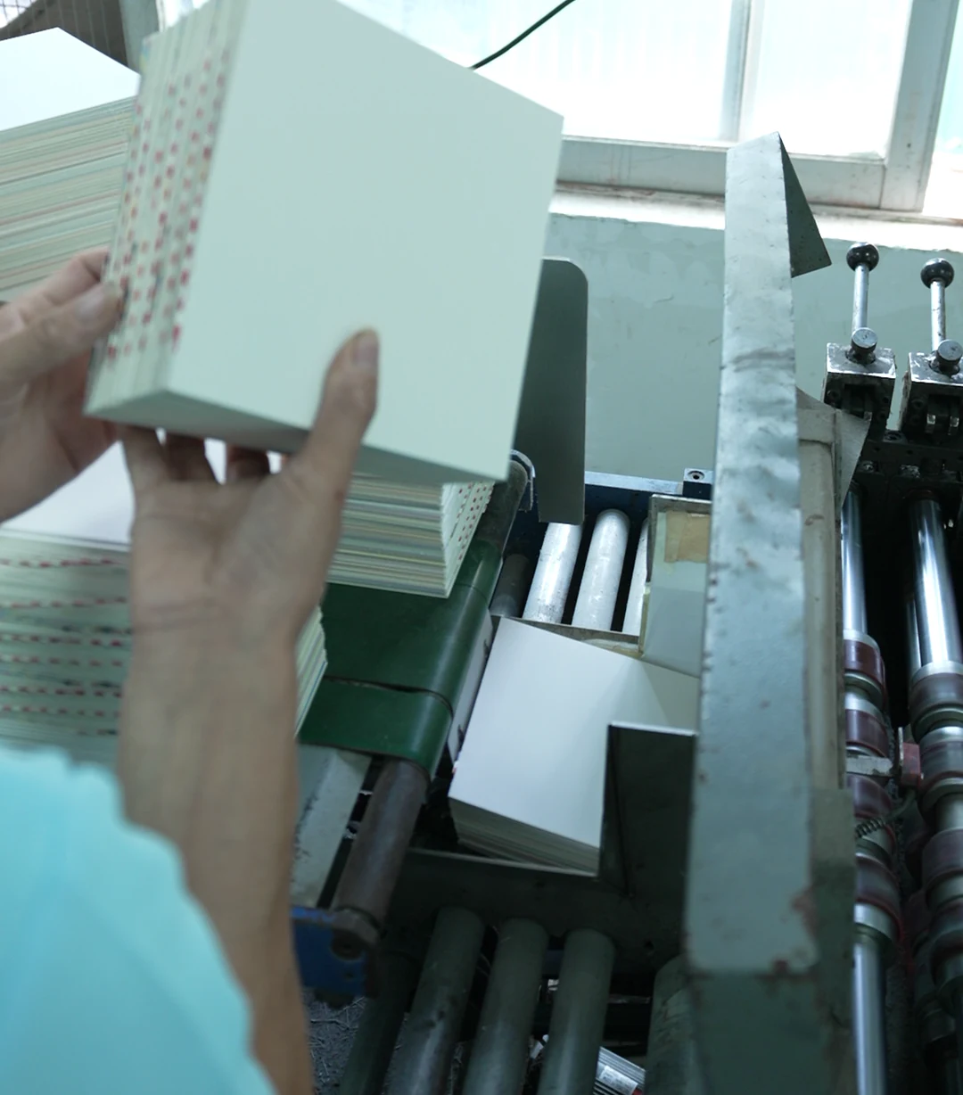 A book block held beside binding equipment, with its folded sections visible.