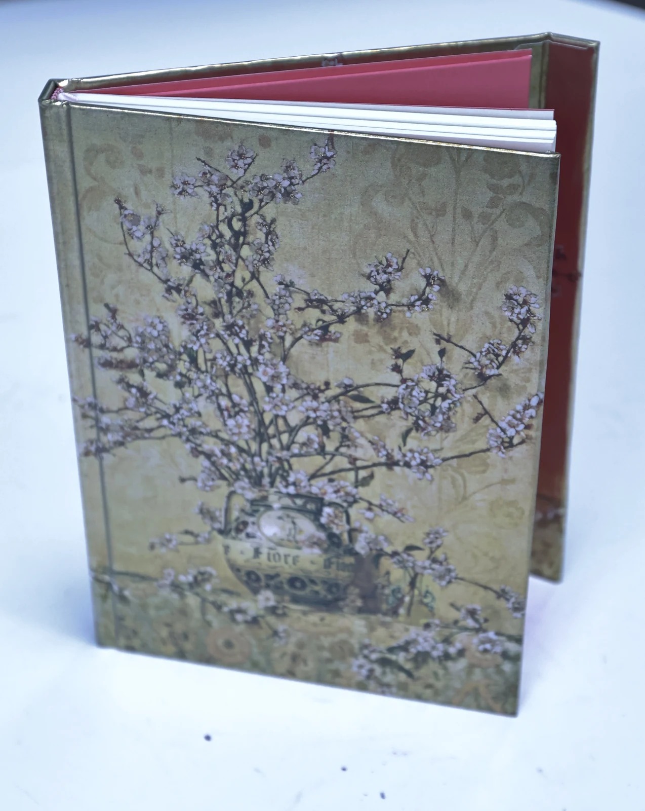 Printed hardcover sample with a floral cover, visible spine and contrasting endpapers.