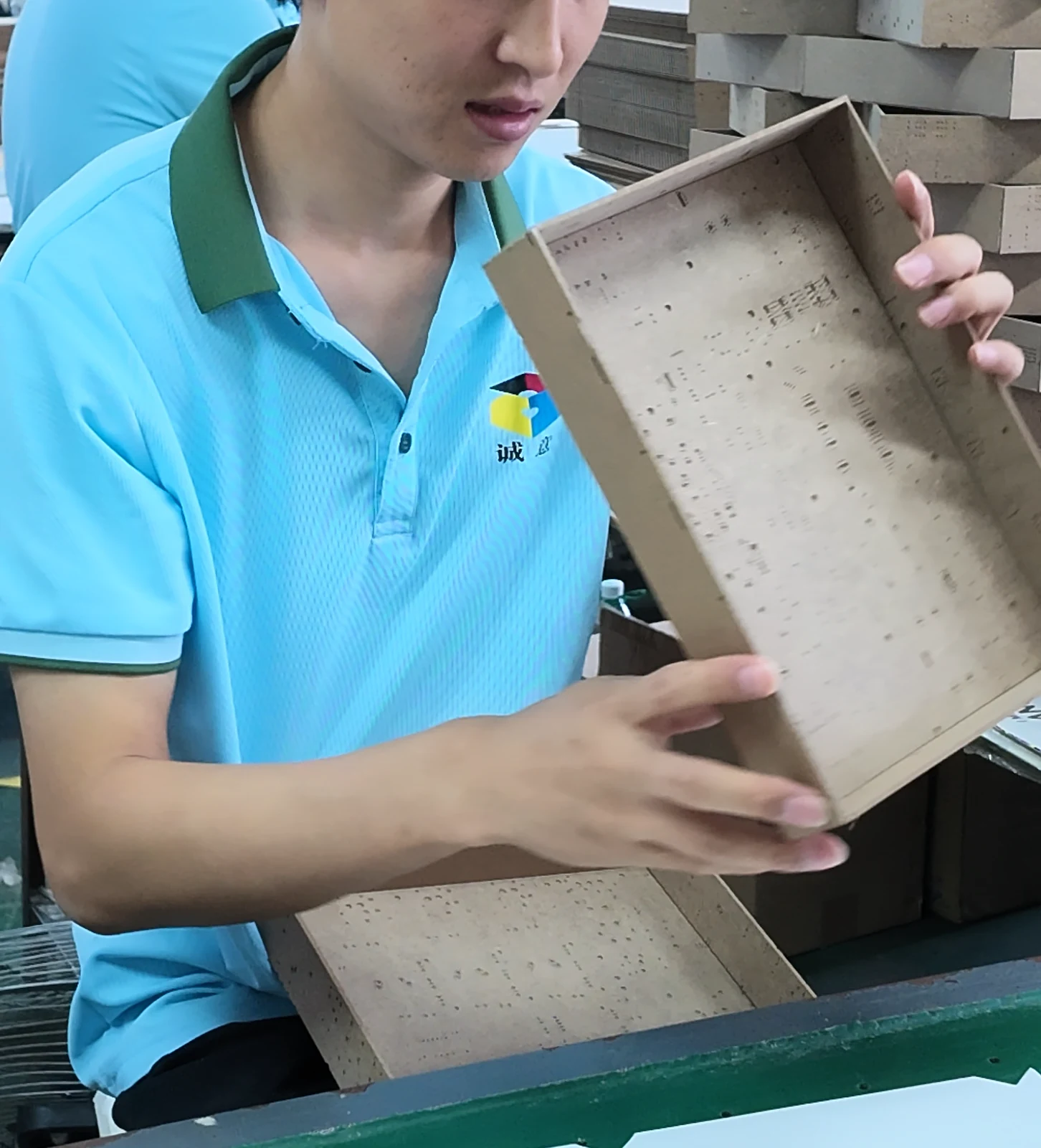 An unfinished rigid box shell held for handling during assembly.