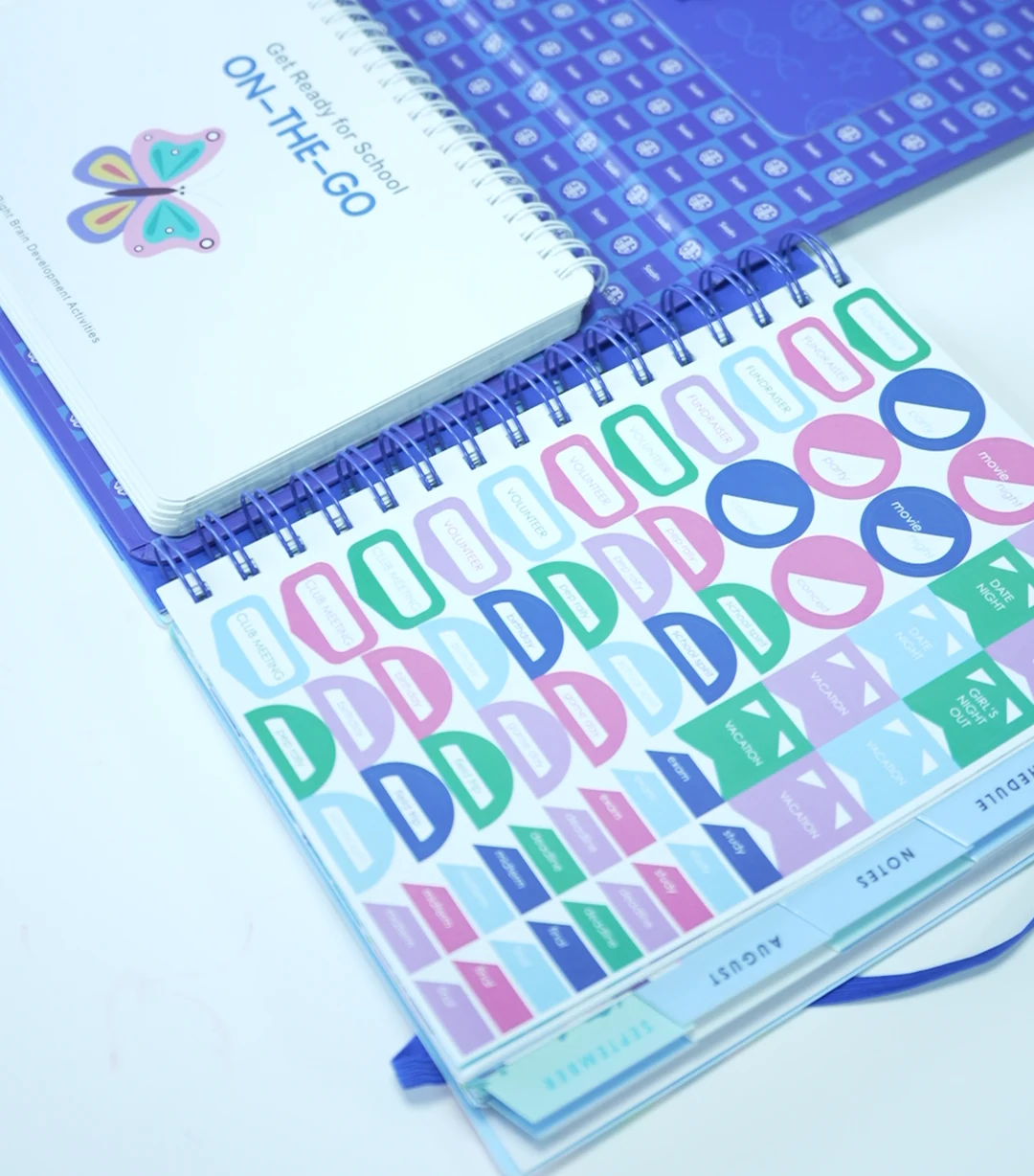 Wire-bound planners with printed covers and a sticker sheet.
